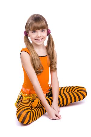 Little girl in the orange dress is sitting on the floor. Portrait of an attractive young teenager is smiling in orange over white background.の写真素材