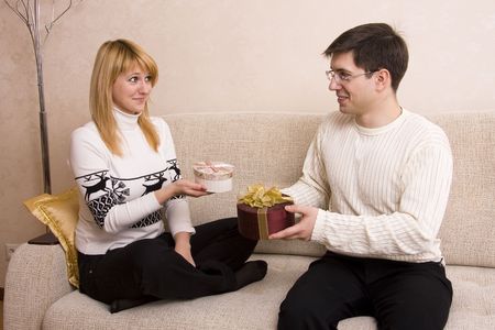 Happy couple. Man is giving gifts woman at Valentines day. Female congratulate  male at Christmas.の写真素材