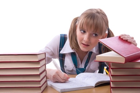 Girl studying hard for exams. Young and beautiful schoolgirl  is wearing a traditional uniform watch furtively at the textbook.の写真素材