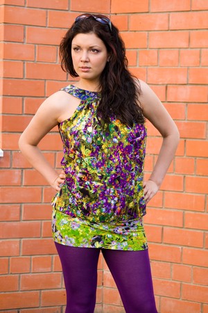 Beautiful woman in brightly coloured dress blouse. A young and attractive female standing on brick backgroundの写真素材