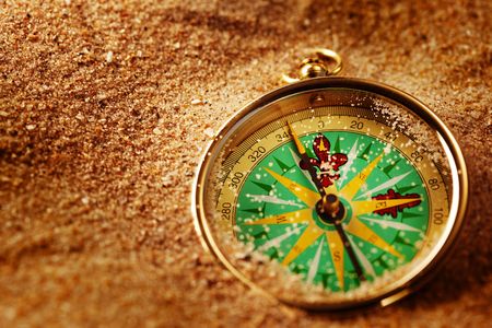 Closeup of a compass laying on a sandの写真素材