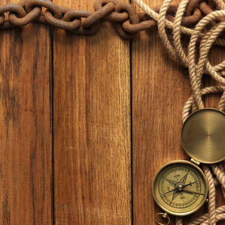 Compass, rope and chain on wooden boardの写真素材