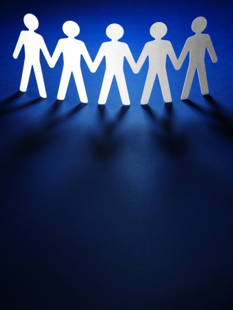 Group of paper people holding hands. Teamwork conceptの写真素材