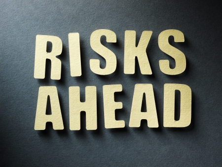 The word Risks Ahead in cut out paper letters on paper backgroundの写真素材