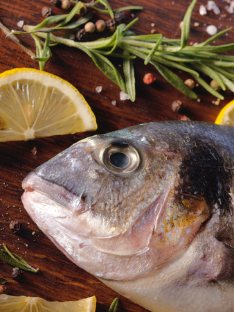 Raw dorado fish with rosemary and sea salt server on old wooden table.の写真素材