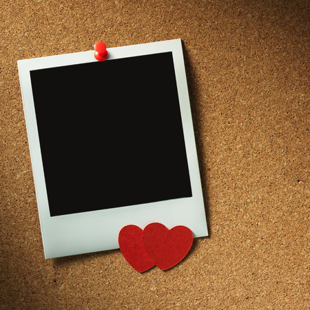 polaroid style photo frames on corkboard with paper heartの写真素材