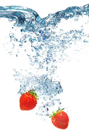 Fresh strawberry dropped into water with splash isolated on whiteの写真素材