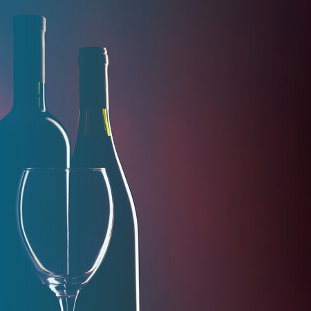 Bottle and glass of red wine on dark red background.Filtered image: cool cross processed vintage effect.の写真素材