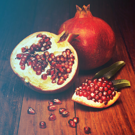 juicy pomegranate open on wood board.Filtered image: warm cross processed vintage effect.の写真素材