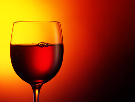 glass of red wine on dark red background. Filtered image: warm cross processed vintage effect.の写真素材