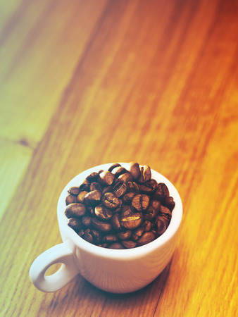 Cup of coffee with coffee beans on a beautiful brown background.Filtered image: vintage effect.の写真素材