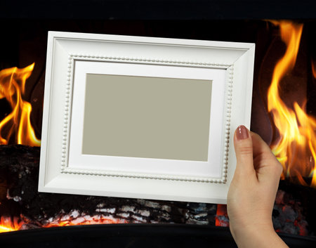 Wooden frame in beautiful woman hands on the background of fire