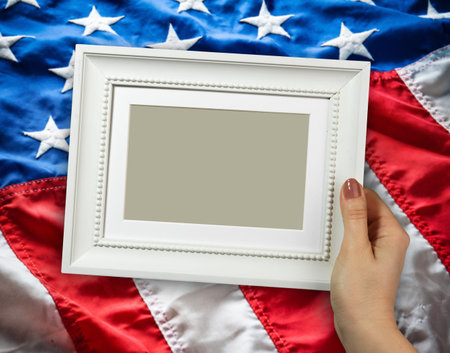 Wooden frame in beautiful woman hands on the background of flapping flag USA with wave