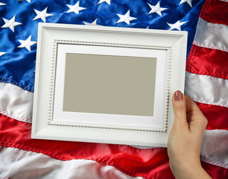 Wooden frame in beautiful woman hands on the background of flapping flag USA with waveの写真素材