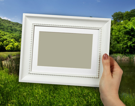 Wooden frame in beautiful woman hands on the countryside scene backgroundの写真素材