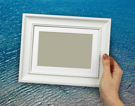 Wooden frame in beautiful woman hands on the Sea water background