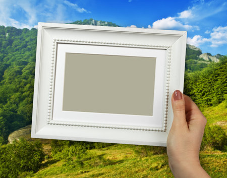 Wooden frame in beautiful woman hands on the Mountain background