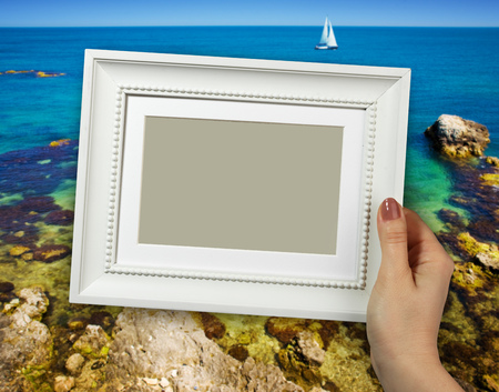 Wooden frame in beautiful woman hands on the sea backgroundの写真素材