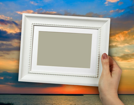 Wooden frame in beautiful woman hands on the background beautiful sunset