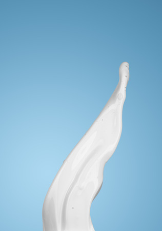 milk or white liquid splash on blue background. isolatedの写真素材