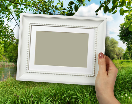 Wooden frame in beautiful woman hands on the background creek in the forestの写真素材
