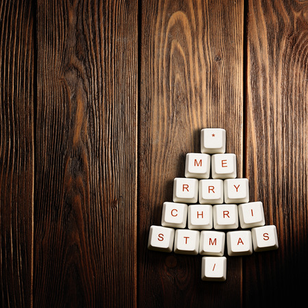 Christmas card - Christmas tree made of computer keys,wooden backgroundの写真素材