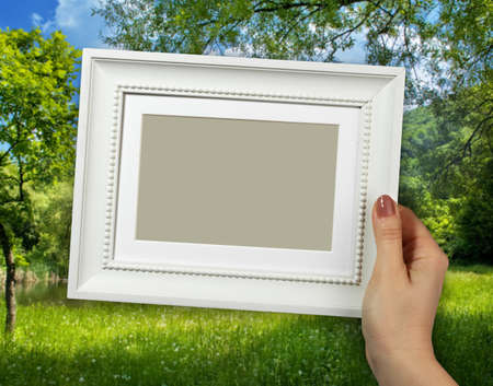 Wooden frame in beautiful woman hands on the countryside scene backgroundの写真素材