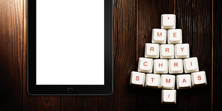 Christmas tree made of computer keys and tablet computer on wooden background . 3d rendering