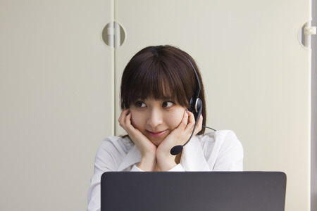 Business woman sitting at her desk with headsetの写真素材