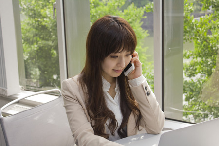 Business woman with mobile phone working in front of Laptop computerの写真素材
