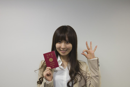 Business woman holding Japanese passport with OK signの写真素材