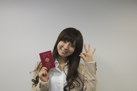 Business woman holding Japanese passport with OK signの写真素材
