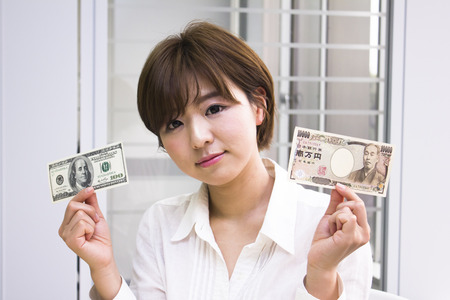 Young woman holding Japanese Yen and US dollarの写真素材