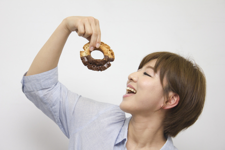 Young woman eating doughnutの写真素材