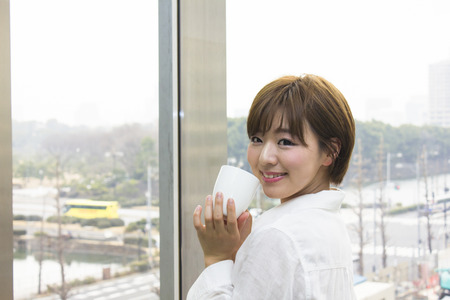 Young businesswoman holding a cup in an officeの写真素材