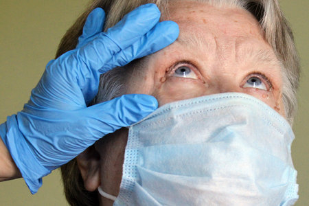 The doctor examines the eyes of an elderly woman with papillomas. At the doctors appointment.