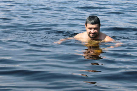 A bearded man swims in the sea. Concept of summer vacation, healthy lifestyle.の写真素材