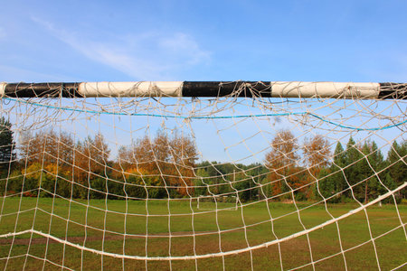 Old football goal against the background of the football field and autumn forest.