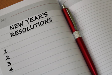 Notepad with a pen on a wooden table. View from above. The concept of resolutions for the new year