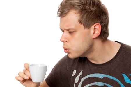 Young man drinking coffee from a coffee cup isolated on white backgroundの写真素材