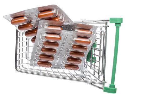 Shop cart with brown capsules blisters on an white backgroundの写真素材