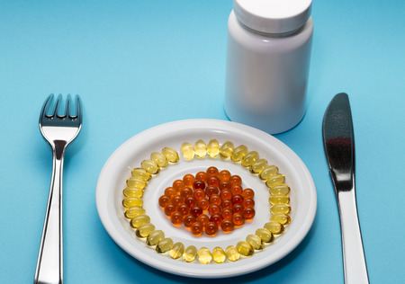 Yellow and red pills on a plate and bottle on blue backgroundの写真素材