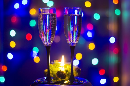 Glasses of champagne and a candle with colorful backgroundの写真素材