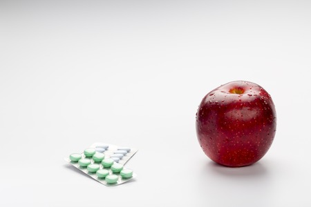 Red apple and colorful pills in blister on white backgroundの写真素材