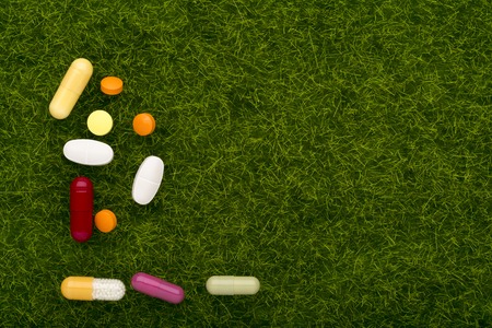 Colorful pills on an green grass background.Top viewの写真素材