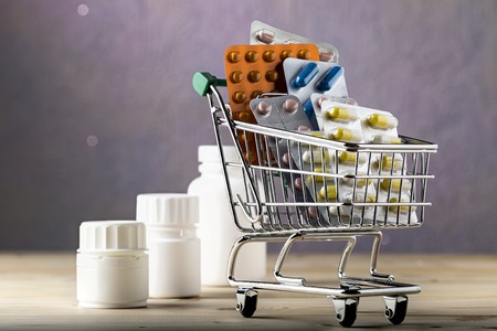 Shopping cart filled with blister packs of colorful pillsの写真素材