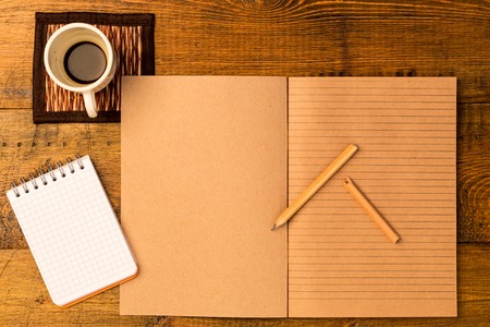 Workplace. Open craft notepad with pencil. Cup of fresh coffeeの写真素材