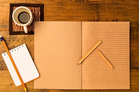Workplace. Open craft notepad with pencil. Cup of fresh coffeeの写真素材