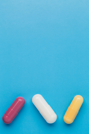 Three multi colored pills on blue backgroundの写真素材