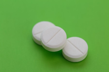 Pile of white pills on green backgroundの写真素材